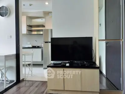 Modern living room with TV and open kitchen layout in stylish apartment.