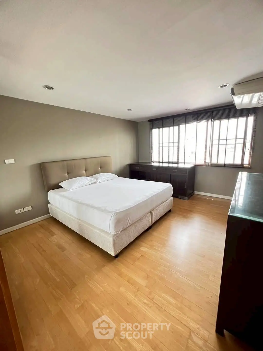 Spacious bedroom with modern decor and large windows for natural light