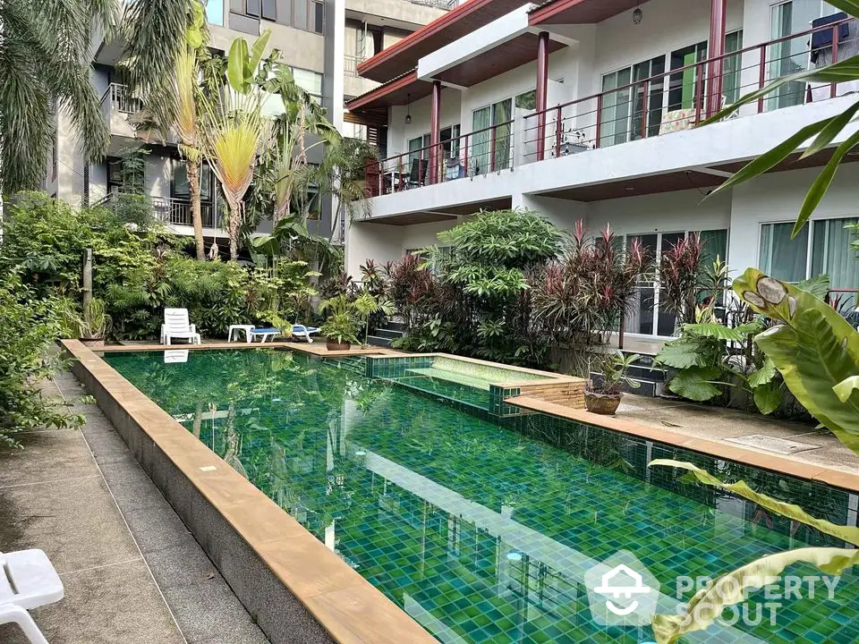 Inviting tropical oasis with a sparkling pool surrounded by lush greenery, nestled within a modern residential complex.