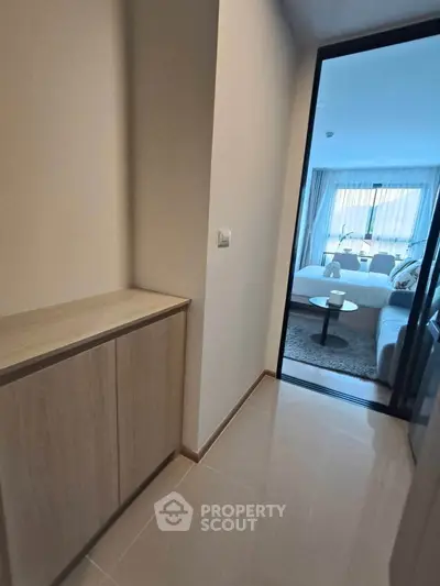 Modern apartment hallway leading to a stylish living room with natural light.