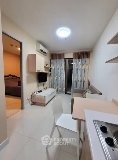 Modern open-plan living room with kitchen and balcony access in a cozy apartment.