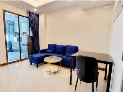 Modern living room with blue sofa and dining area in a stylish apartment.