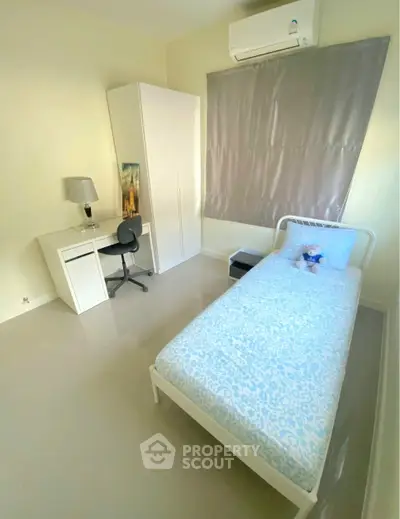 Cozy bedroom with single bed, study desk, and air conditioning in modern apartment.