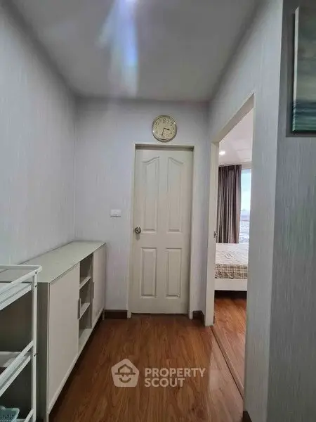 Cozy hallway leading to a bright bedroom with wooden flooring and modern decor.