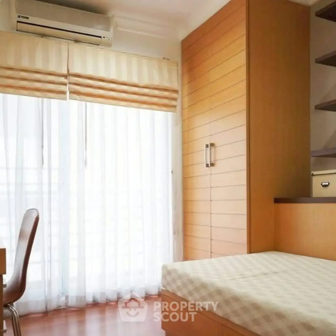 Bright bedroom with large window and modern wooden furniture