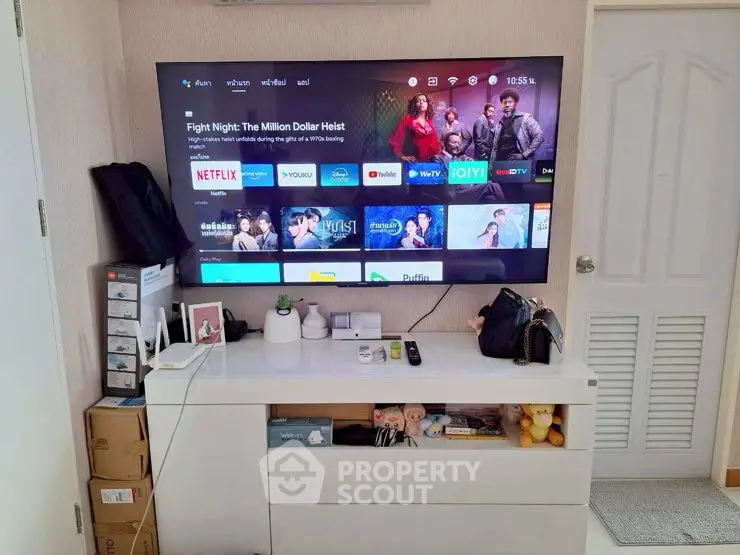 Modern living room with large wall-mounted TV and sleek storage unit.