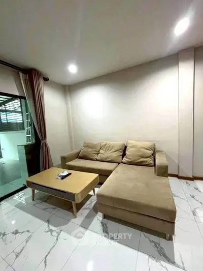 Modern living room with beige sectional sofa and sleek coffee table on marble floor.