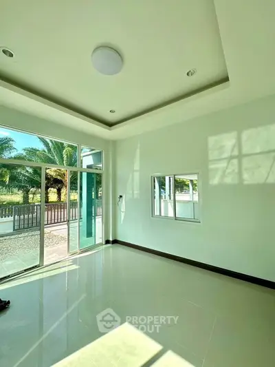 Bright and spacious living room with large windows and garden view, perfect for modern living.
