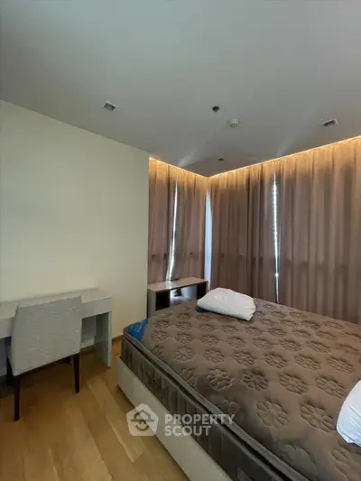 Spacious bedroom with elegant lighting and modern furnishings in a luxury apartment.