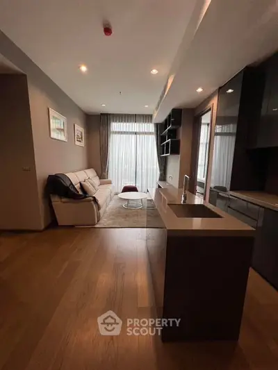 Modern living room with open kitchen, featuring sleek design and natural light.