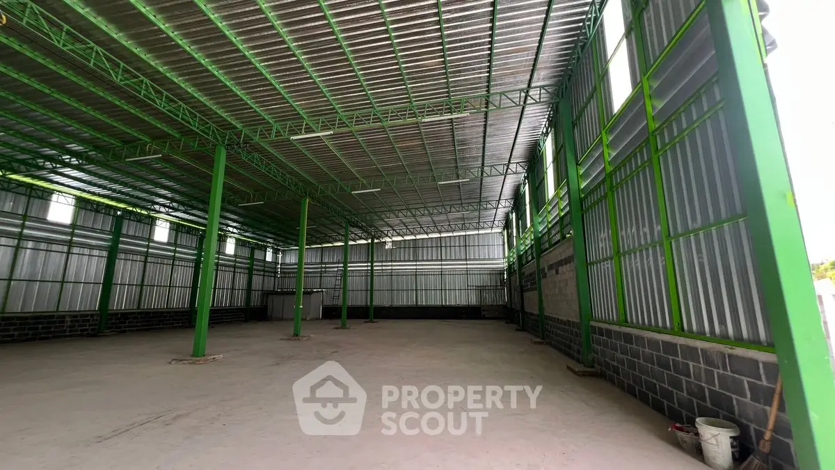 Spacious industrial warehouse with high ceilings and green steel framework