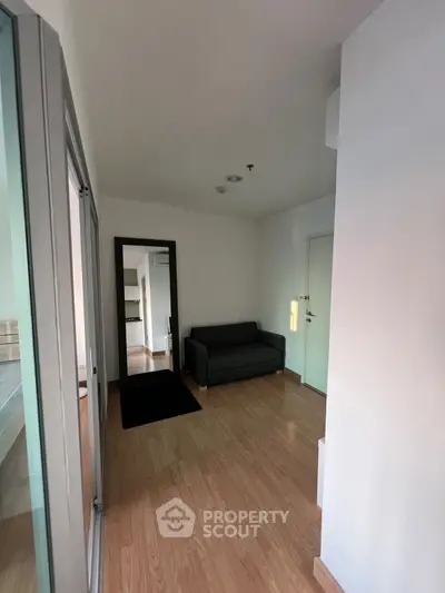 Cozy modern apartment interior with sleek wooden flooring and stylish gray sofa.