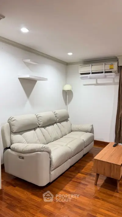 Cozy living room with plush sofa and air conditioning, perfect for relaxation.