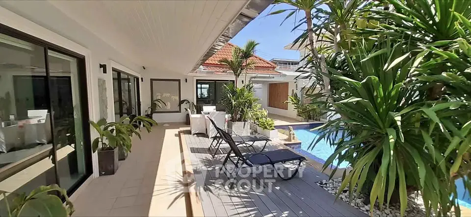 Luxurious poolside patio with lush greenery and modern outdoor furniture