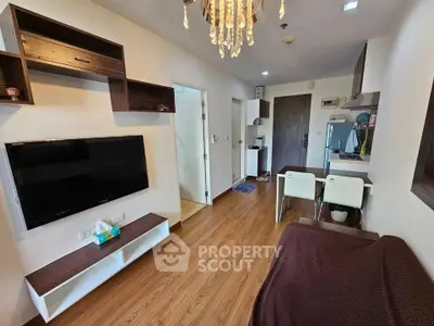 Modern living room with wooden flooring, wall-mounted TV, and stylish chandelier in a cozy apartment.