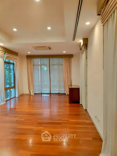 Spacious living room with hardwood floors and large windows for natural light.
