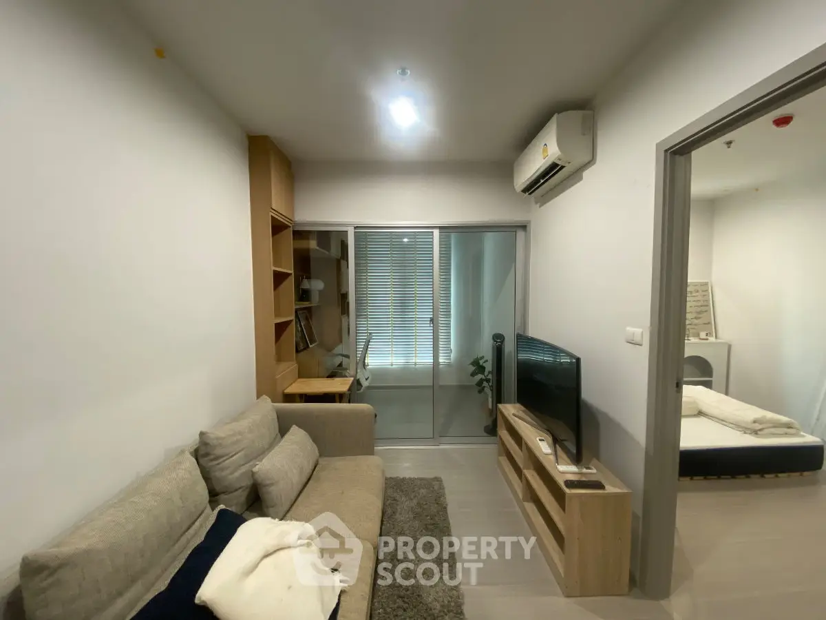 Modern living room with cozy sofa, TV, and air conditioning, leading to a bedroom through sliding doors.