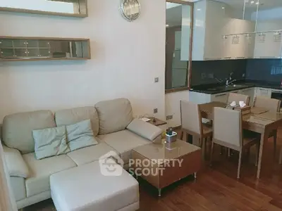 Modern living room with open kitchen, featuring sleek furniture and stylish decor.