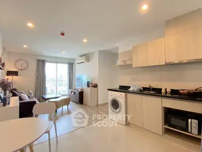 Modern open-plan living room and kitchen with city view, featuring washing machine and stylish decor.
