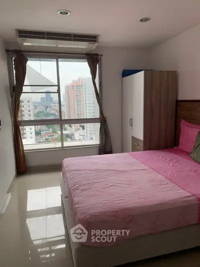 Cozy bedroom with city view, featuring large window and stylish decor.