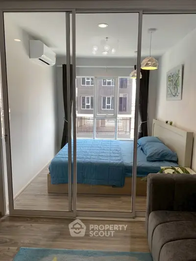 Modern bedroom with glass sliding doors and blue bedding in a stylish apartment.