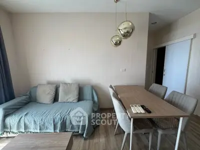 Modern living room with cozy sofa and dining area, featuring stylish pendant lights and wooden flooring.