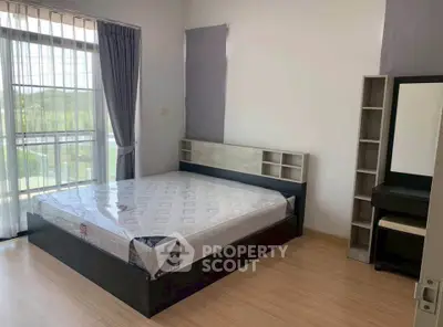 Spacious bedroom with large window and modern furnishings in a bright apartment.
