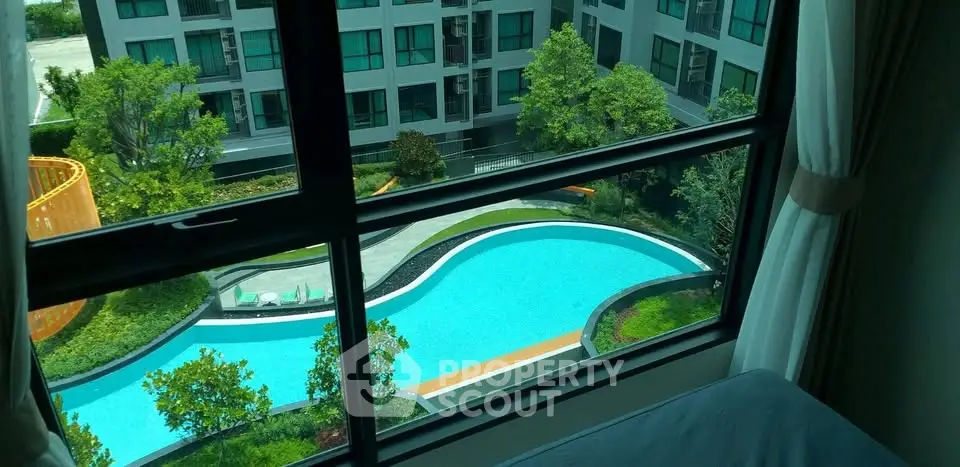 Stunning view of modern apartment complex with pool from window, perfect for urban living.