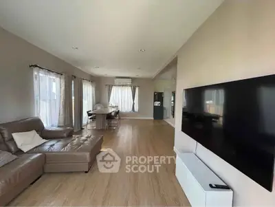Spacious modern living room with large TV and elegant dining area, featuring natural light and stylish decor.