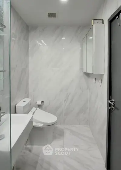 Modern bathroom with sleek white marble tiles and contemporary fixtures.