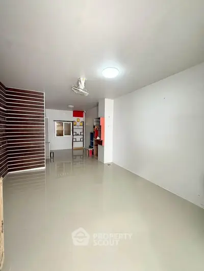 Spacious empty room with glossy tiled floor and modern ceiling light