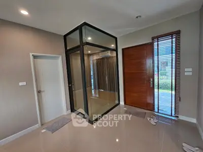 Modern interior with glass enclosure and wooden door, showcasing sleek design and natural light.