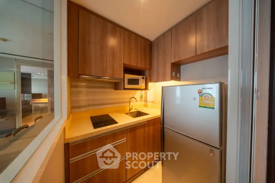Modern kitchen with wooden cabinets, sleek appliances, and cozy lighting.