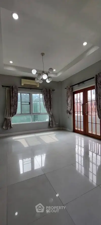 Spacious living room with modern lighting and large windows for natural light.