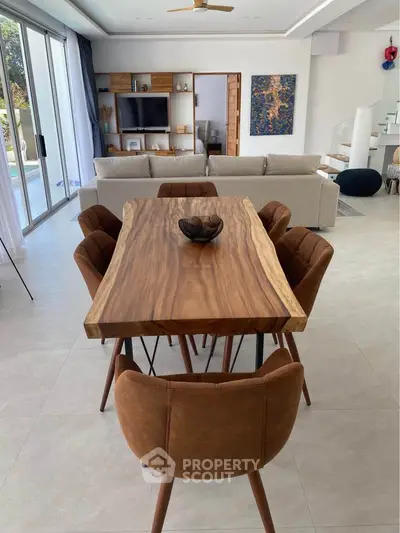 Modern dining area with wooden table and stylish chairs in open-plan living space.