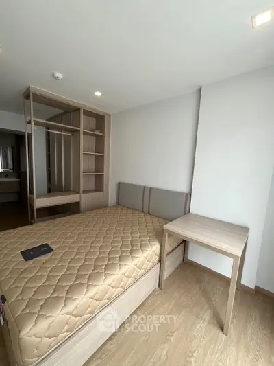 Modern bedroom with wooden flooring and built-in wardrobe, featuring a cozy bed and a small desk.