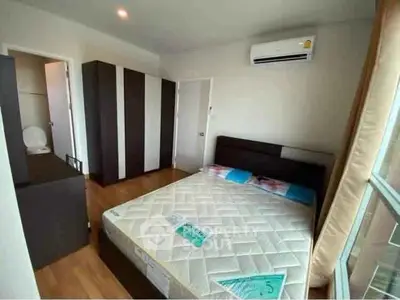 Modern bedroom with air conditioning and large window, featuring a comfortable bed and wardrobe.