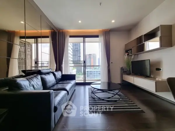 Modern living room with sleek black sofa and city view from large windows.