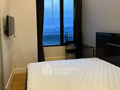 Modern bedroom with city view, featuring a cozy bed and sleek desk setup.