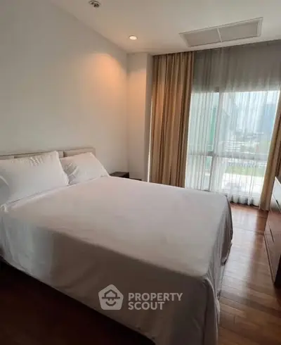 Cozy bedroom with large window and elegant curtains, offering a serene ambiance and natural light.