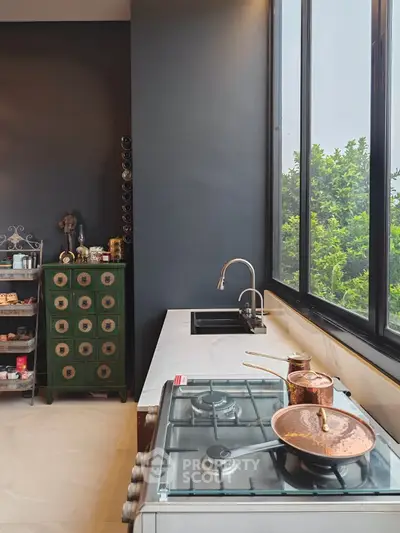 Chic modern kitchen with sleek gas stove, stylish dark cabinetry, and expansive window offering lush green views, perfect for culinary enthusiasts.