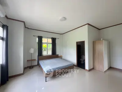 Spacious bedroom with modern furnishings and large windows for natural light.