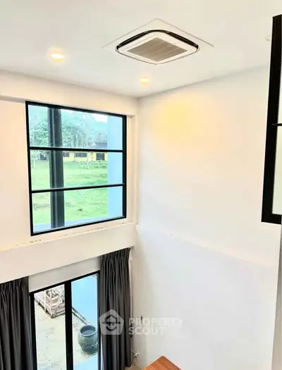 Modern high-ceiling room with large windows and recessed lighting, offering a bright and airy atmosphere.