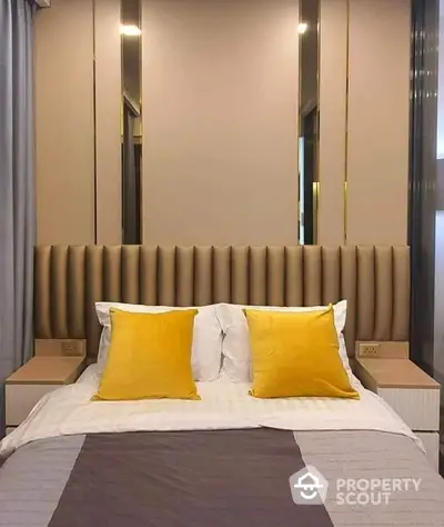 Elegant bedroom with plush headboard and striking yellow accent pillows, featuring mirrored bedside tables and ambient lighting for a luxurious feel.