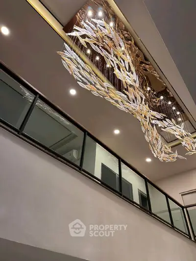 Luxurious modern interior with stunning chandelier and glass railing, showcasing elegance and sophistication.