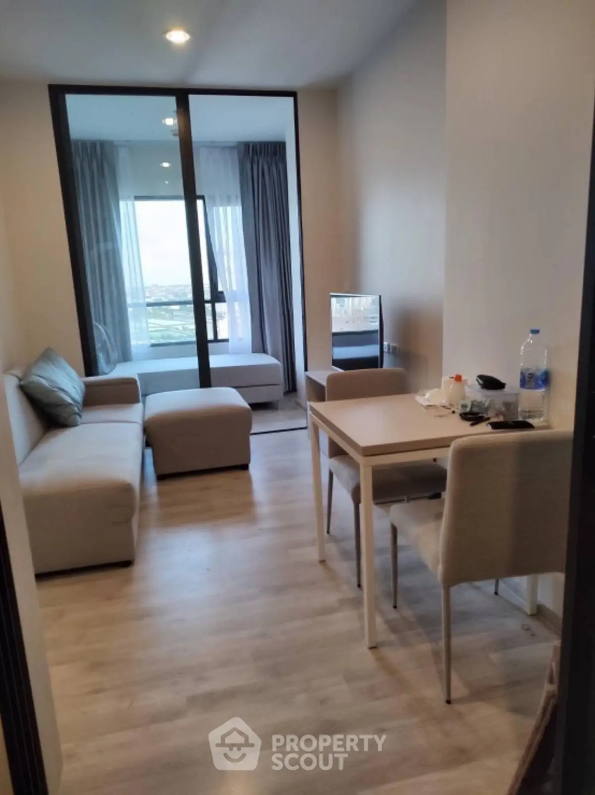 Modern apartment living room with cozy seating and dining area, featuring a view of the bedroom.