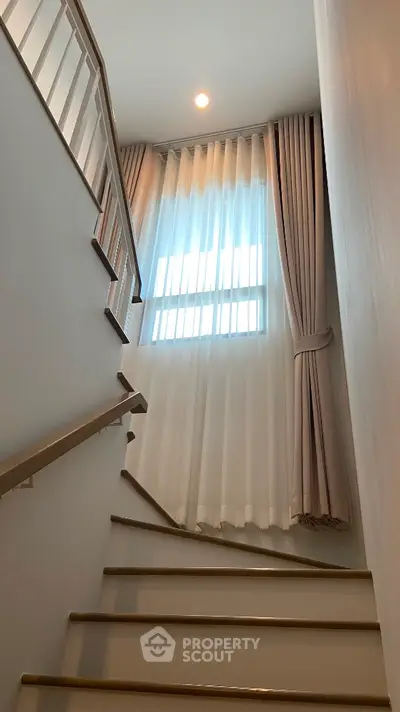 Elegant staircase with natural light and modern curtains in a stylish home