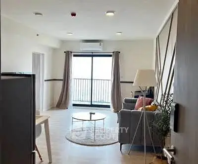 Modern living room with stylish decor and large window balcony view.