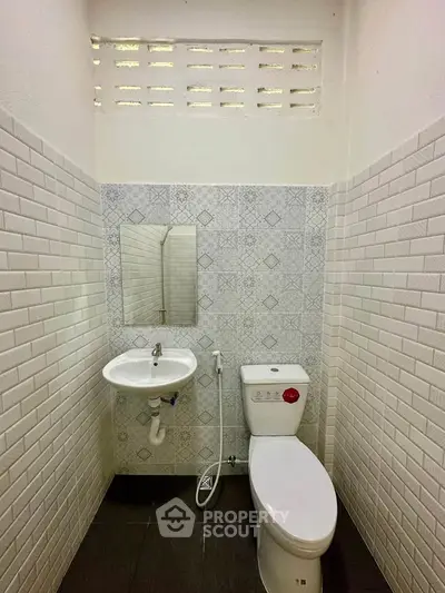 Compact bathroom with modern white tiles and essential fixtures.