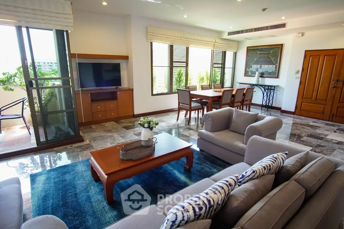 Spacious living room with modern decor and large windows opening to a balcony, perfect for relaxation.